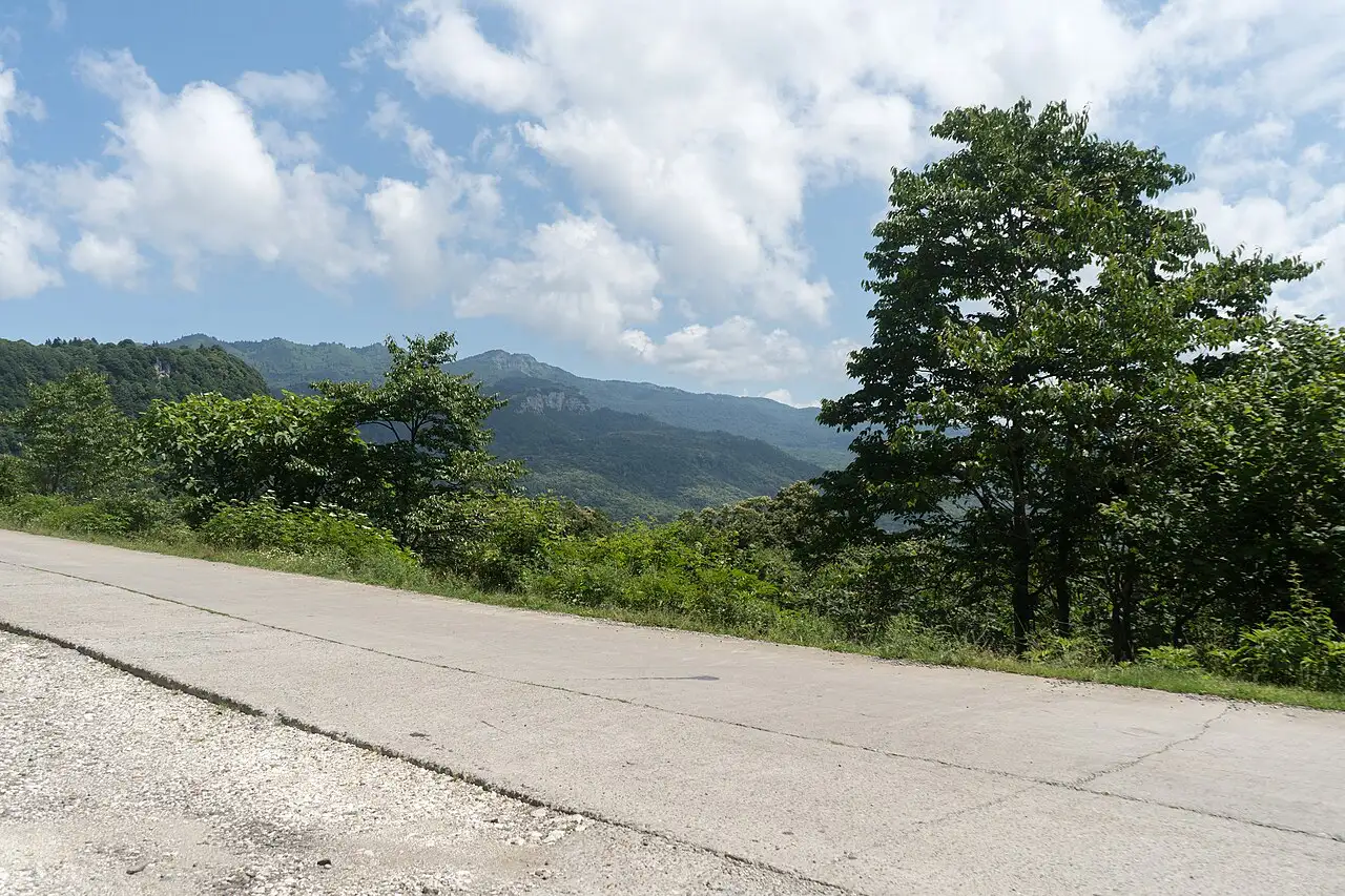 Empty paved road curving through green hills in western Georgia