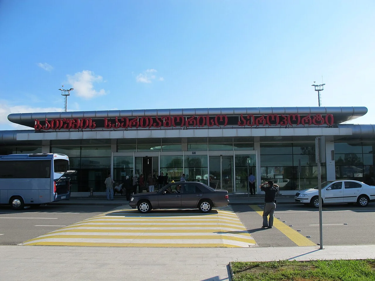 Batumi airport terminal building with cars and a bus parked outside