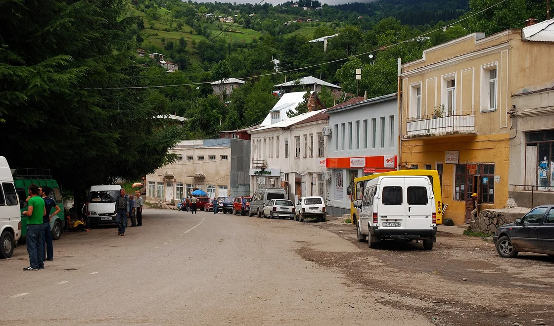 The main street in Khulo: minibuses and cars along the road, green slopes behind the houses