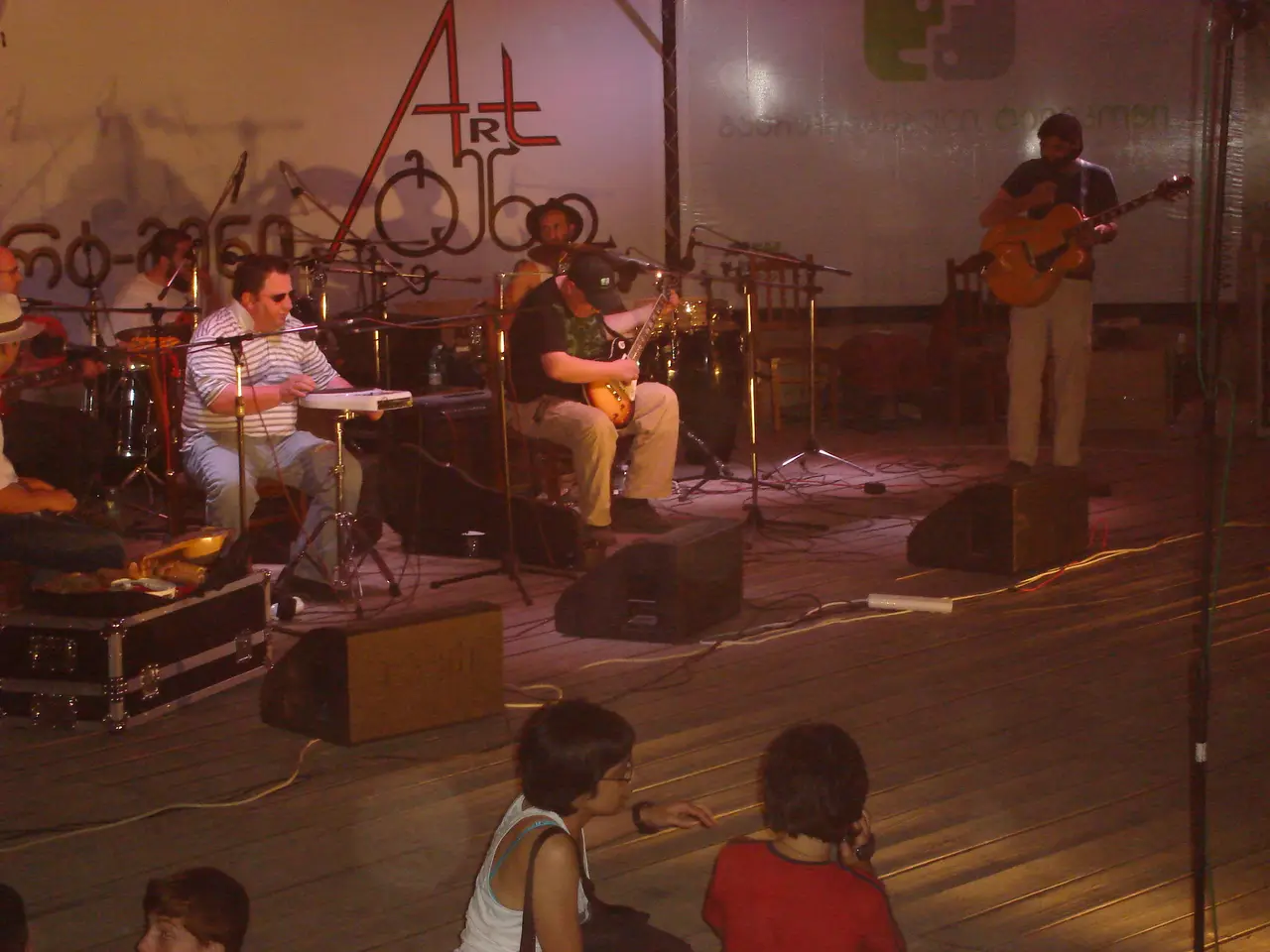 Band playing on a lit stage in front of a large Art-Gene banner in Georgian script