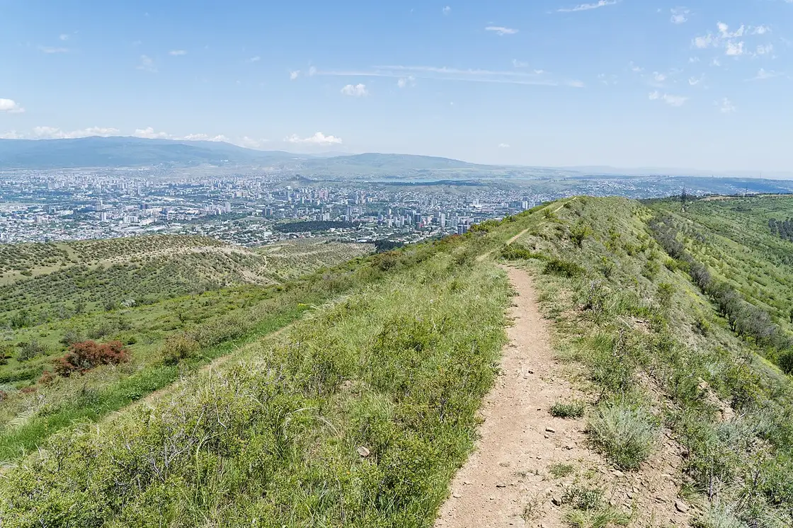 Green ridge trail above Tbilisi with the city spread out below
