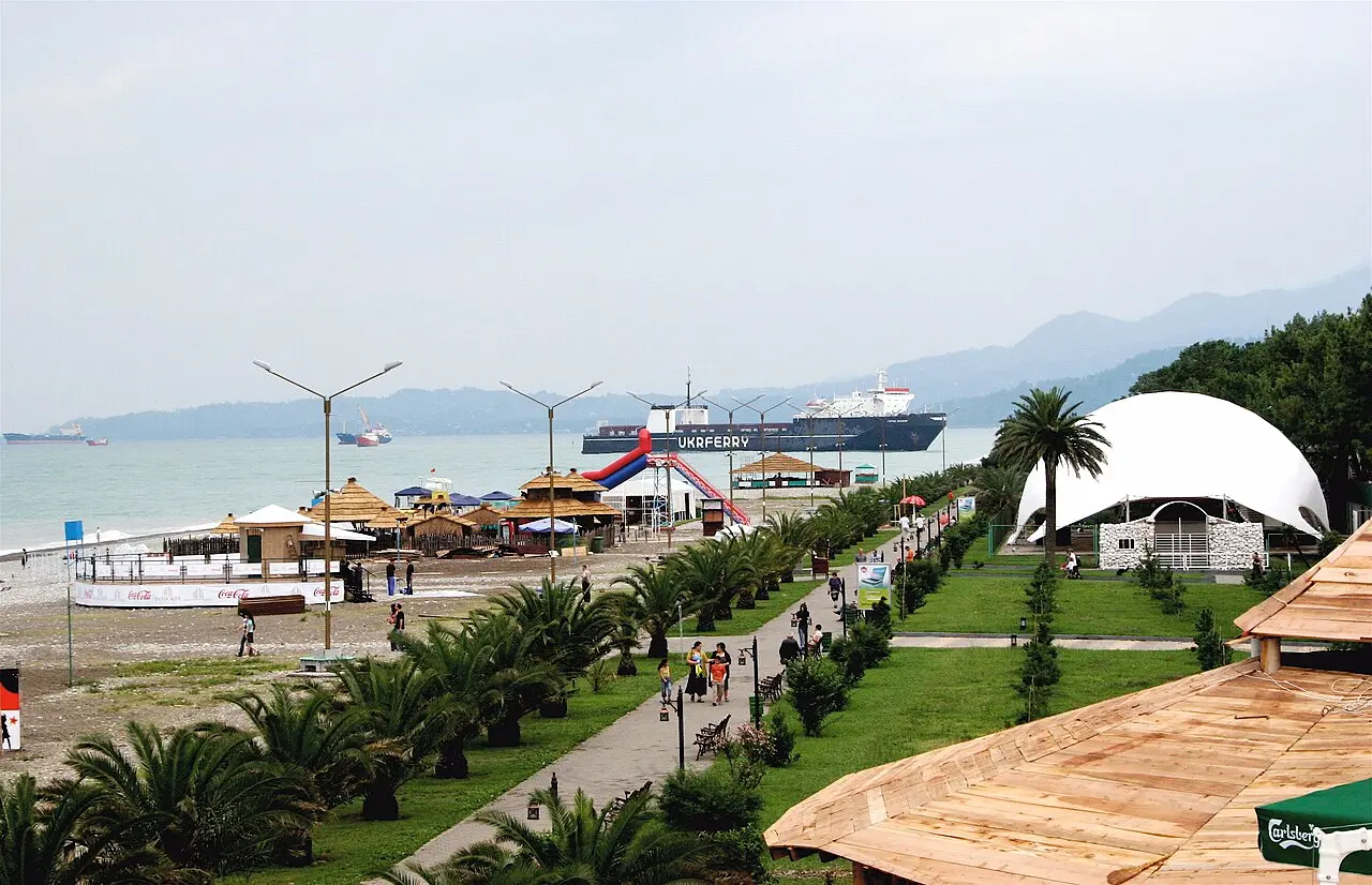 Batumi seafront with palms, beach bars and a ferry on the horizon