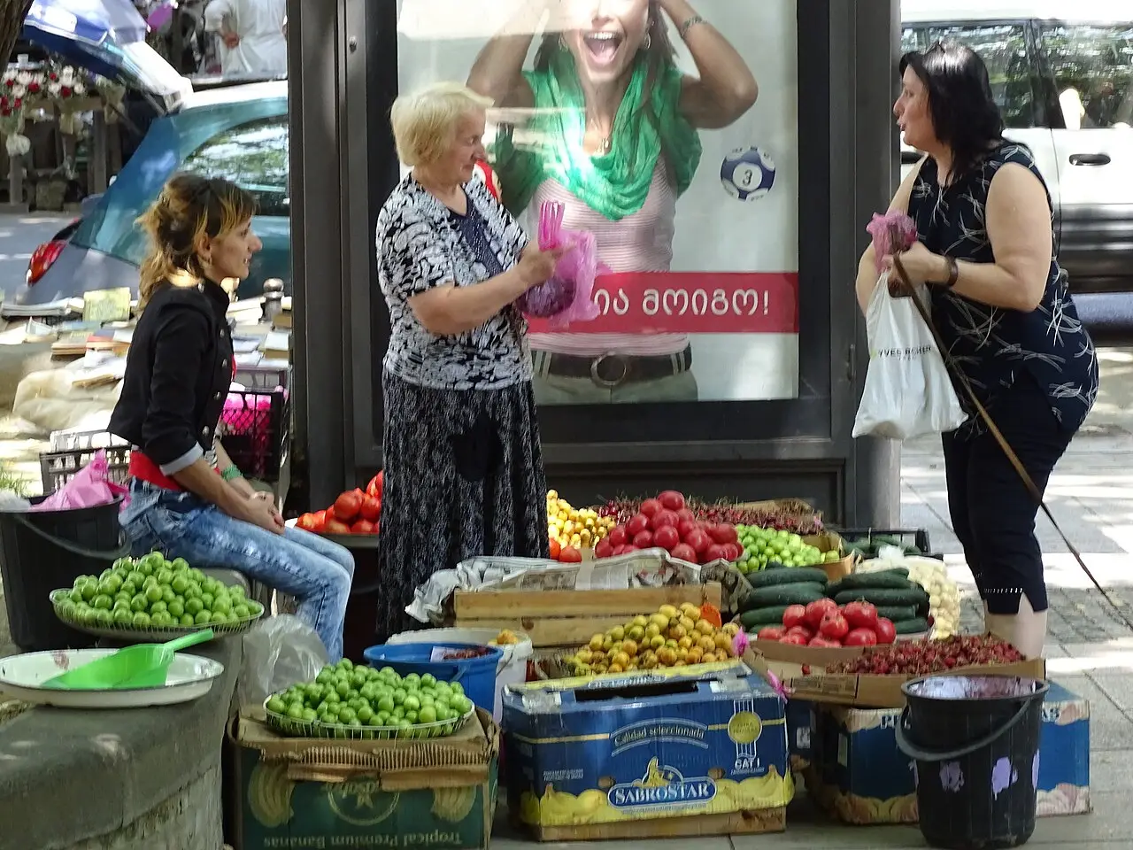 Women at a market stall in Tbilisi with vegetables and greens