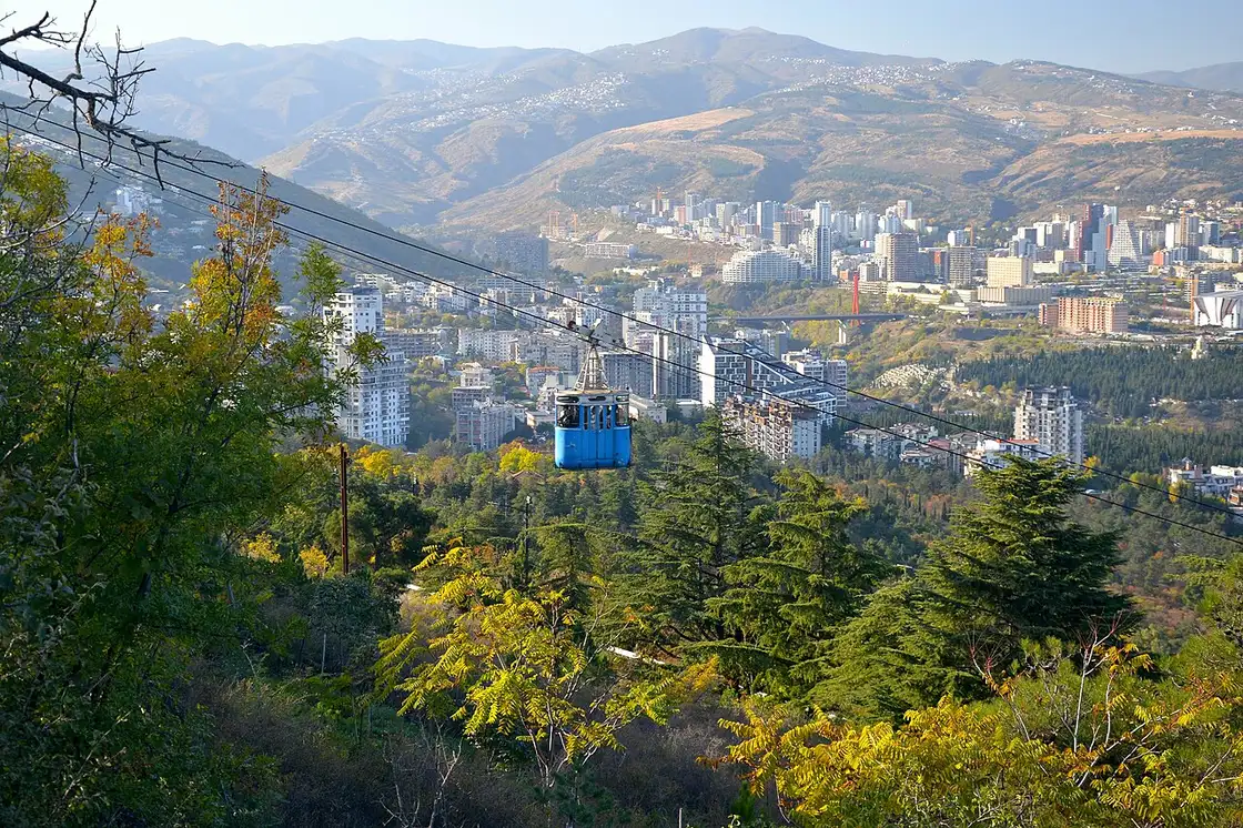 A cable-car cabin above a green slope on the way to the lake
