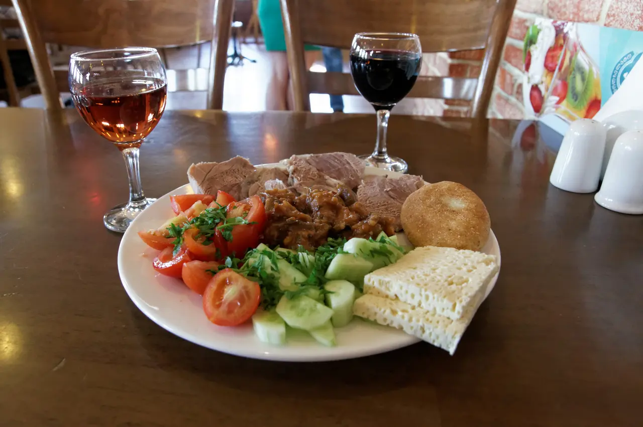 A spread of Georgian dishes with amber and red wine on the table
