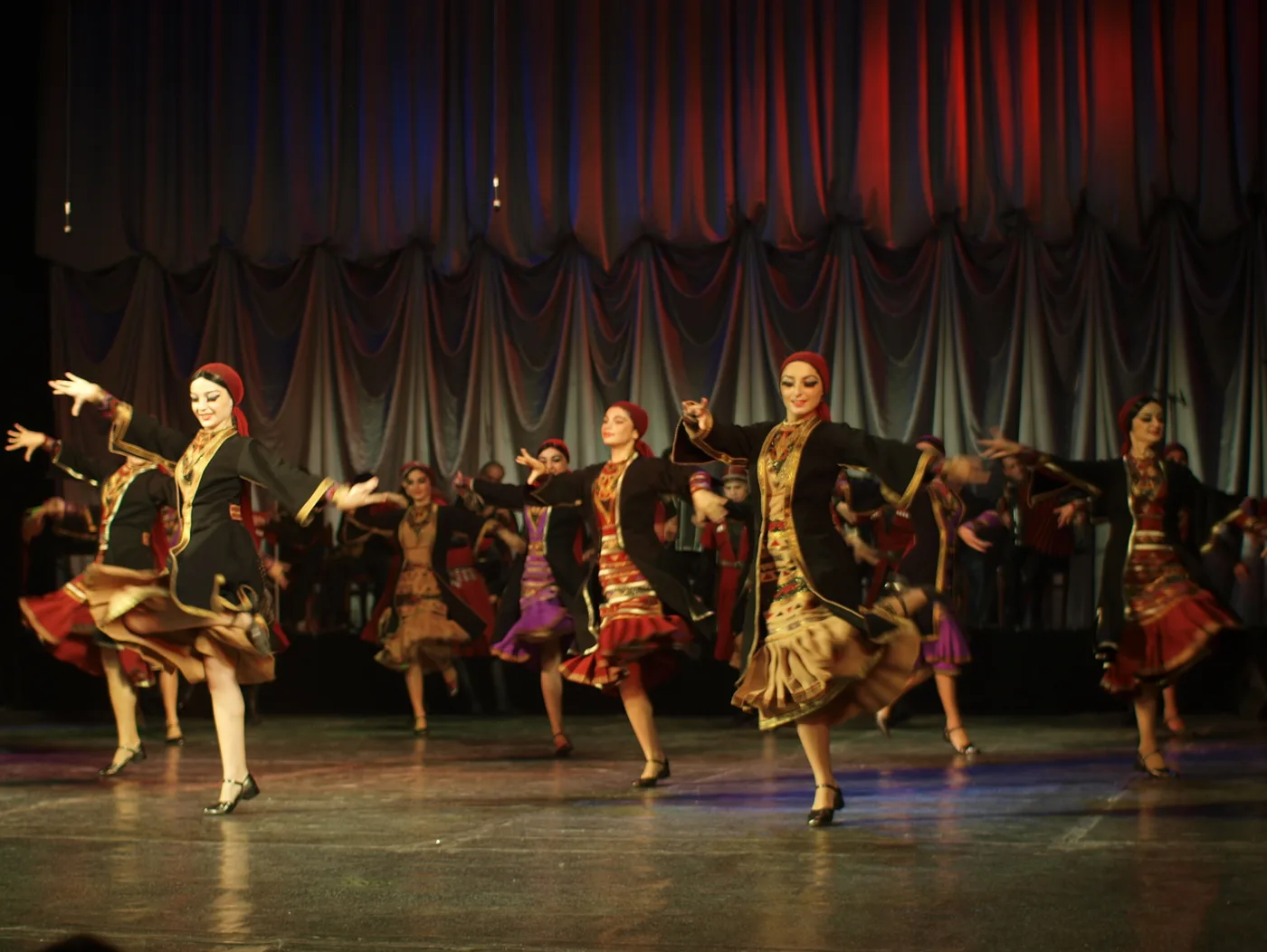 Khevsuruli dance on a Batumi stage: dancers in dark folk costumes with red curtains behind
