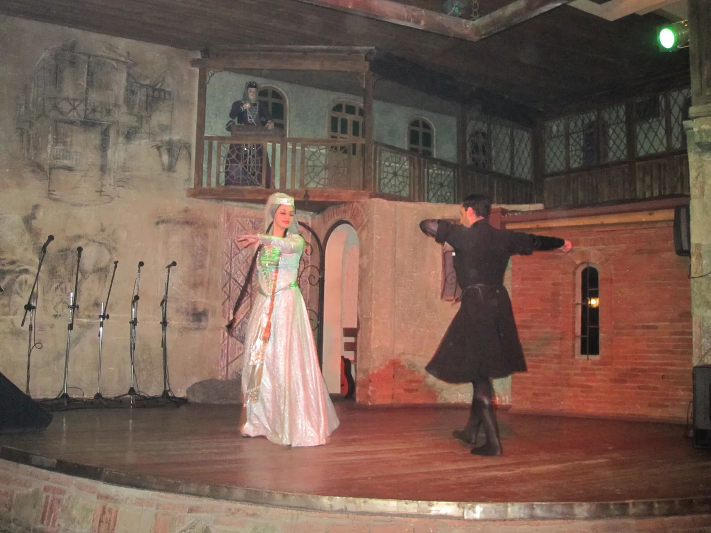 A couple dancing the Kartuli on a theatre stage set made to look like an old Tbilisi courtyard