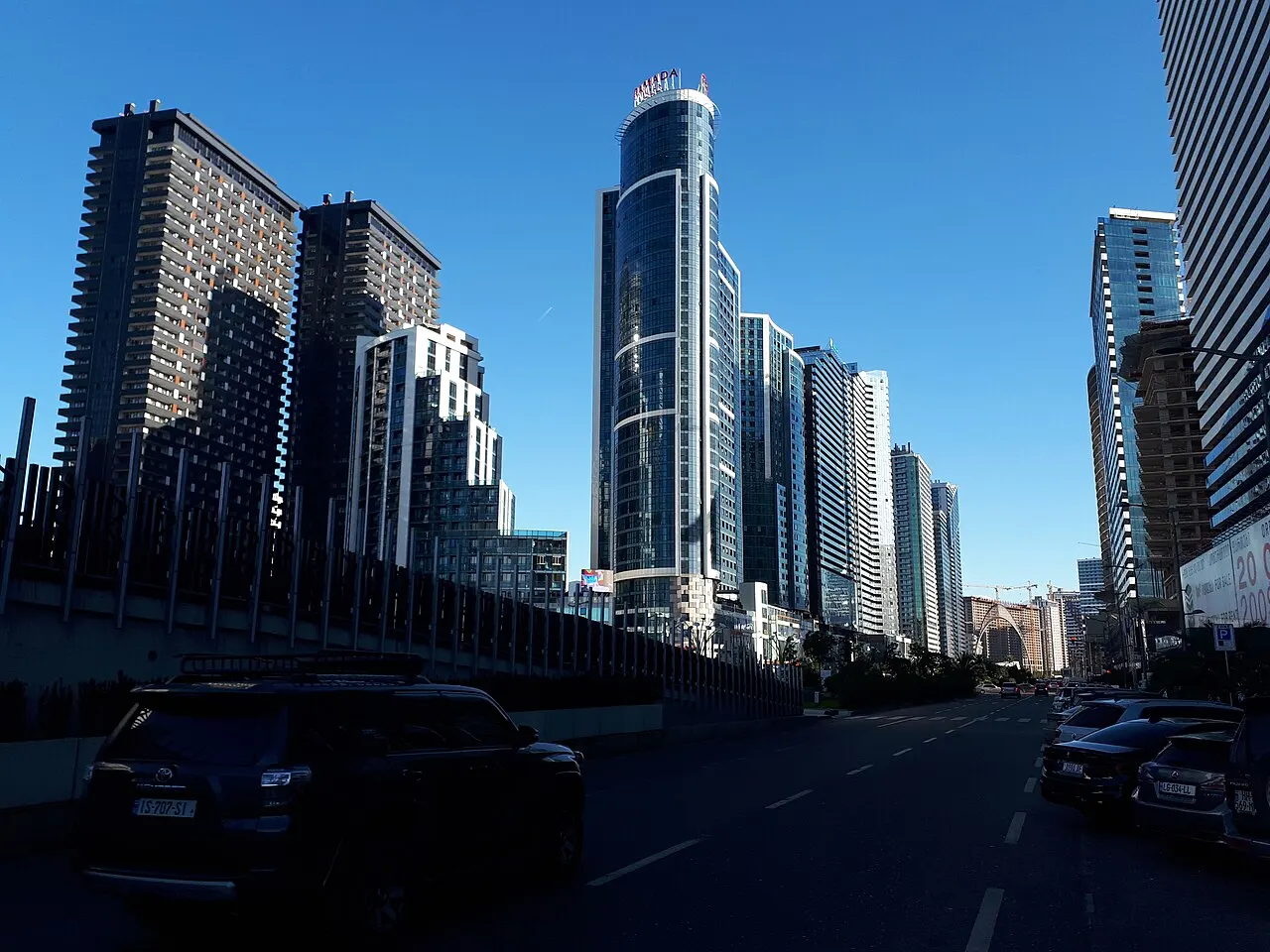 Row of glass skyscraper hotels along a wide boulevard in New Batumi under a clear sky