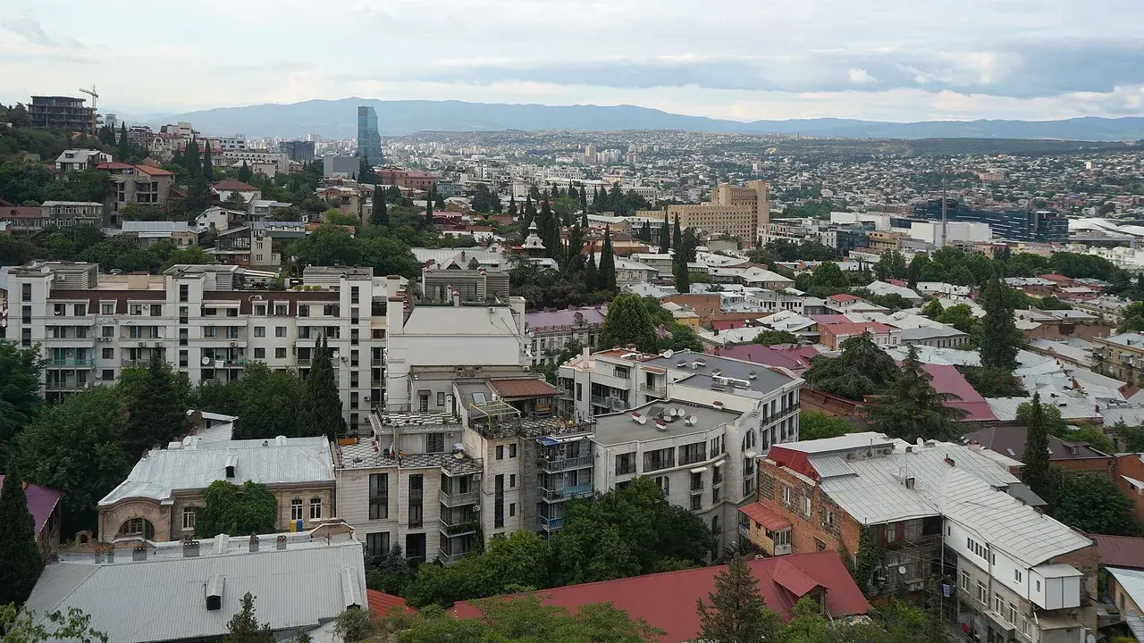 Rooftops of central Tbilisi from above, with mountains on the horizon