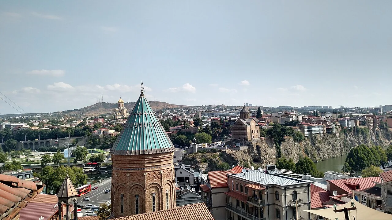 Old Tbilisi from above: an Armenian church dome, the cliff with Metekhi church, Sameba cathedral in the distance