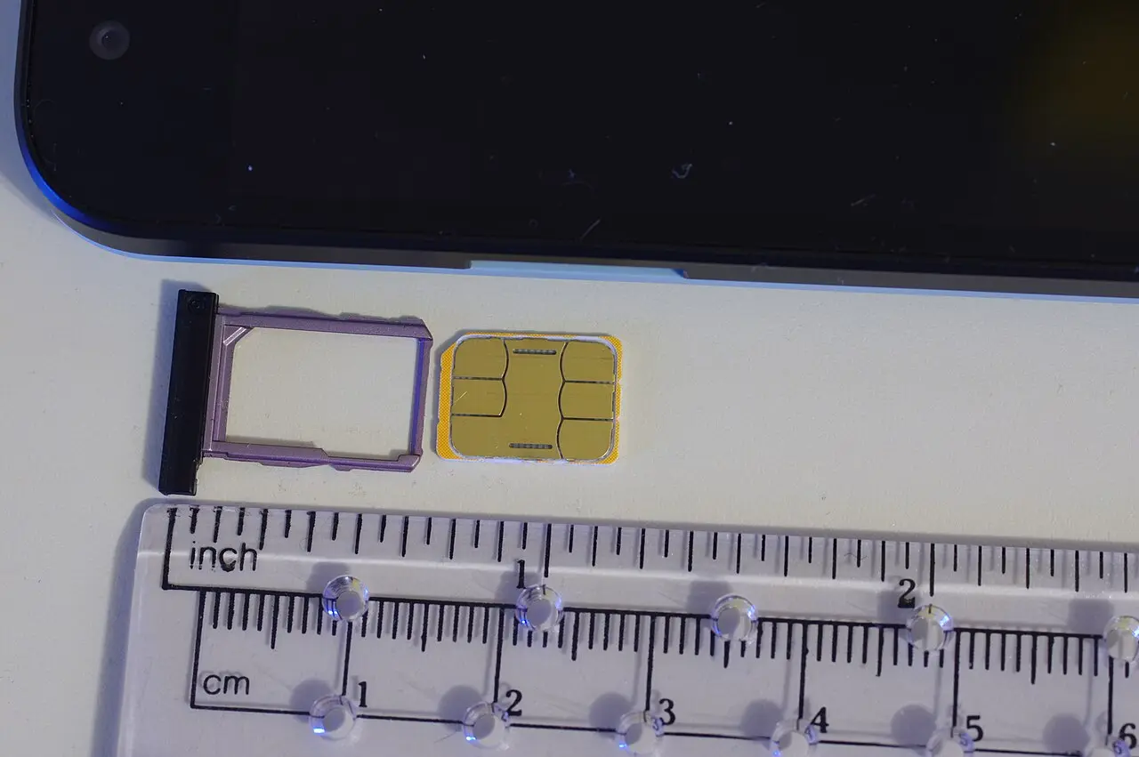 A nano-SIM card next to a smartphone tray