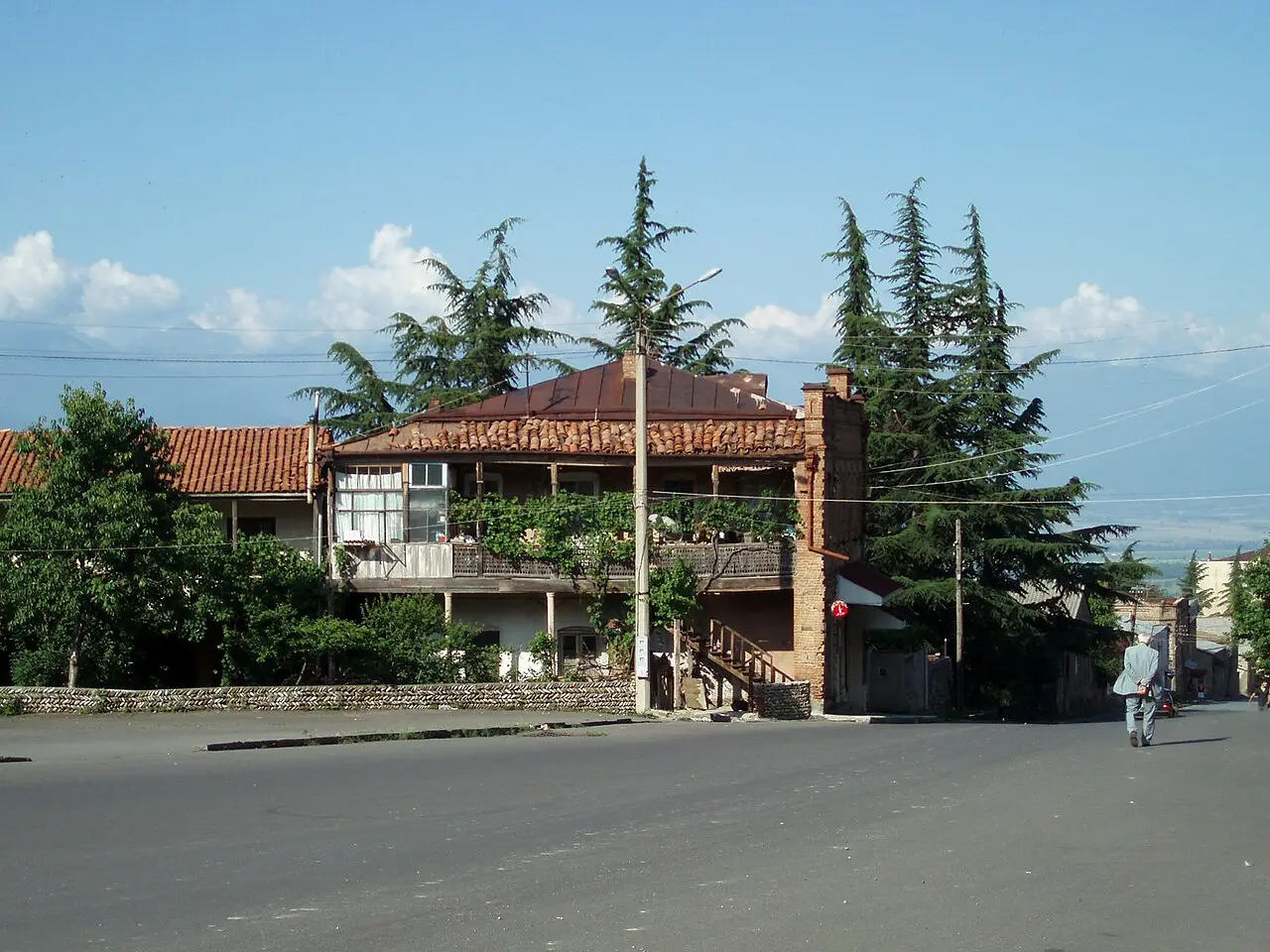 A Telavi street: a house with a vine-covered wooden balcony, cypresses and the hazy Alazani Valley beyond