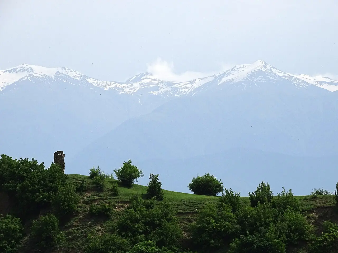 A green hillside near Alaverdi with the snowy Greater Caucasus in the haze