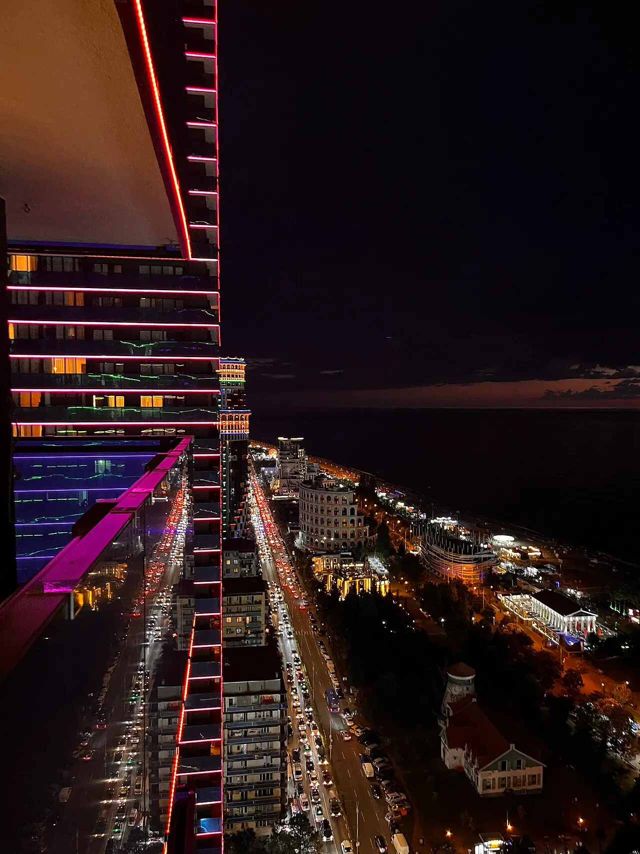 A lit-up New Batumi high-rise at night above the seafront