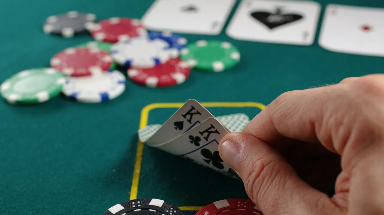 A hand holding cards over chips at a casino gaming table