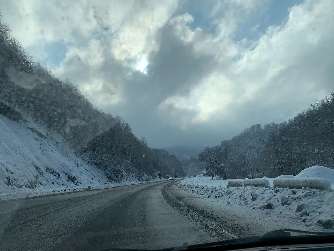 A snowy stretch of the S1 highway seen from a car: a snow-covered slope with bare trees on the left, snowy woods and a bank of snow along the verge on the right