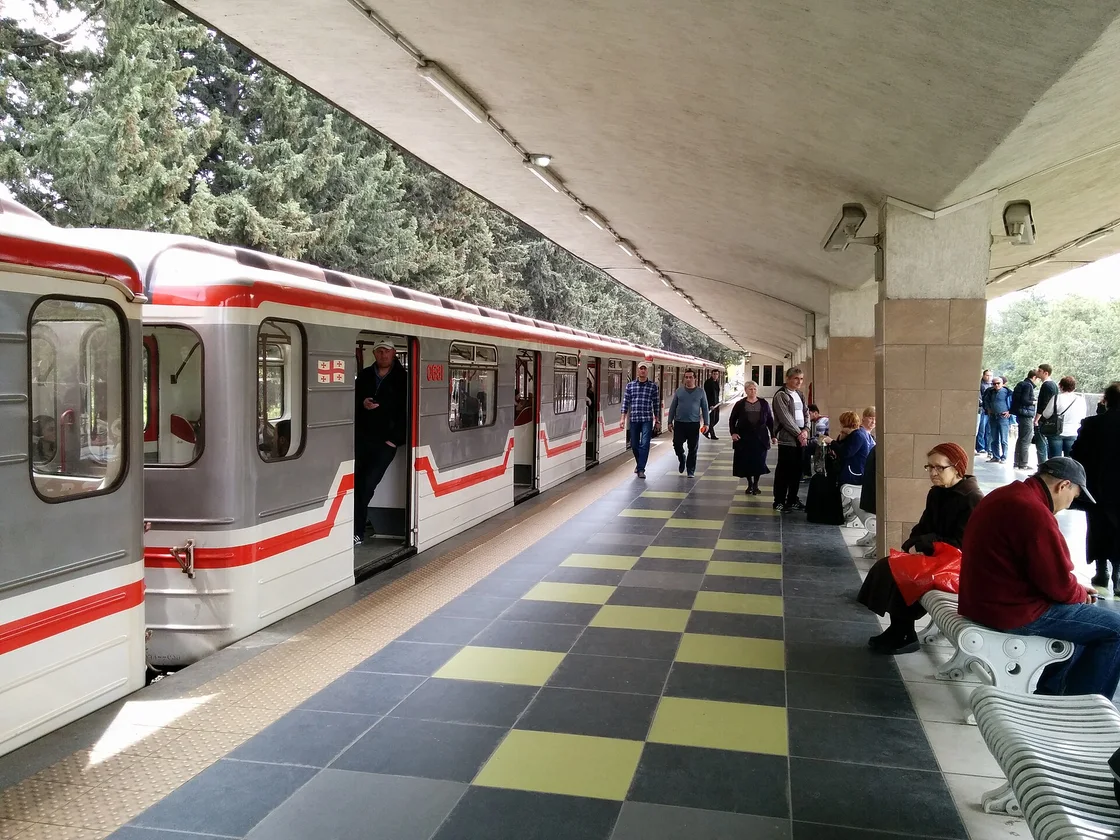 The platform at Didube metro station in Tbilisi: a train with open doors and passengers on a tiled platform