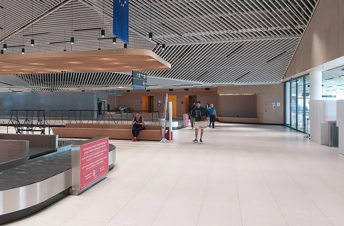The baggage reclaim hall at Kutaisi airport: a carousel, a pale floor and a slatted wooden ceiling