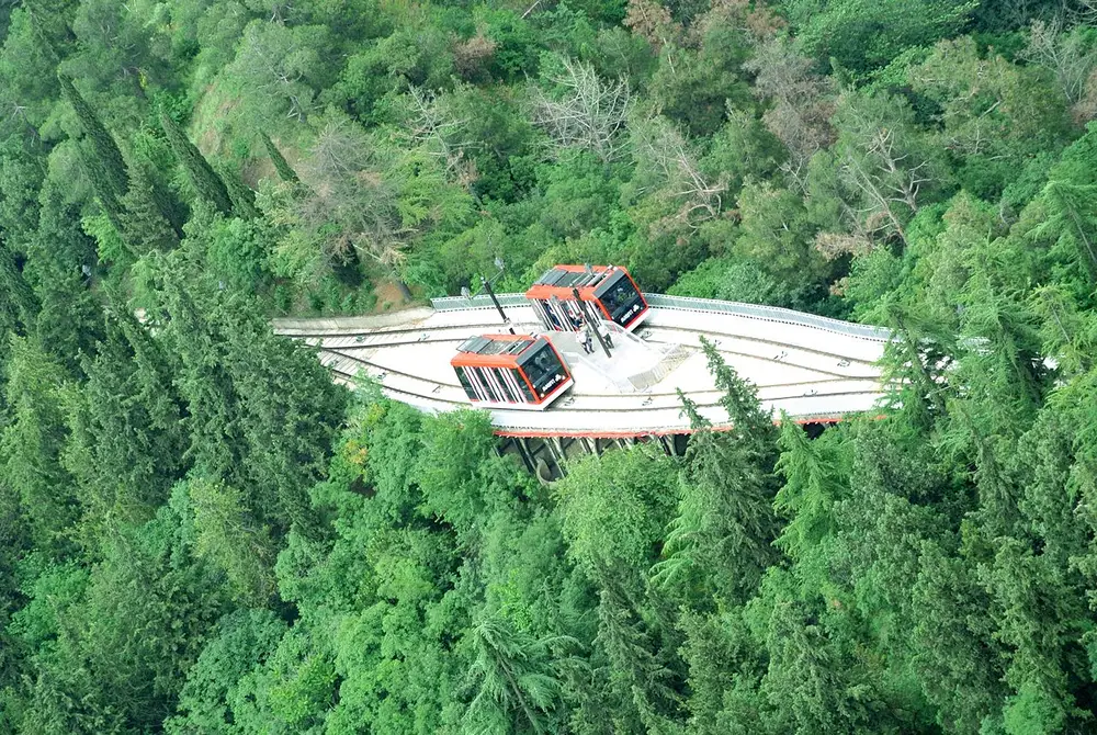 A funicular station on the slope of Mtatsminda amid pine forest, seen from above