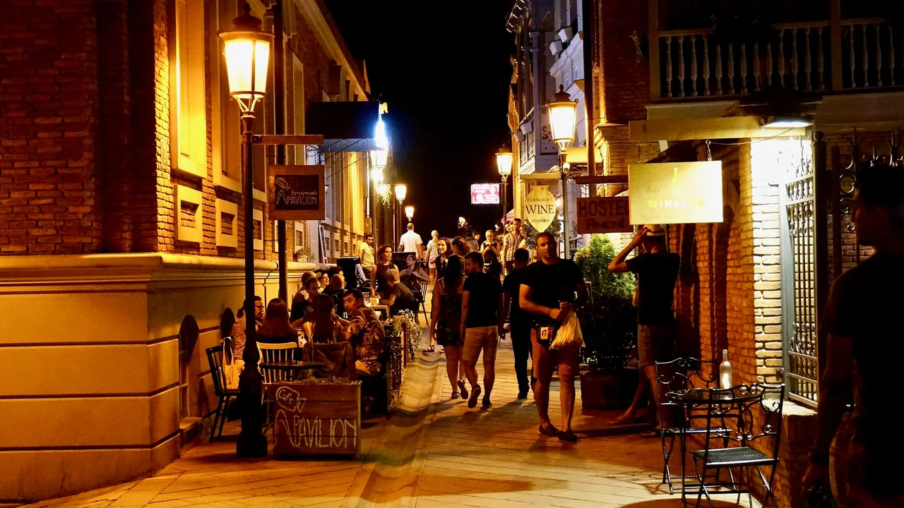 Shavteli Street in the Old Town of Tbilisi at night, with people walking past lit cafe terraces and wine bar signs