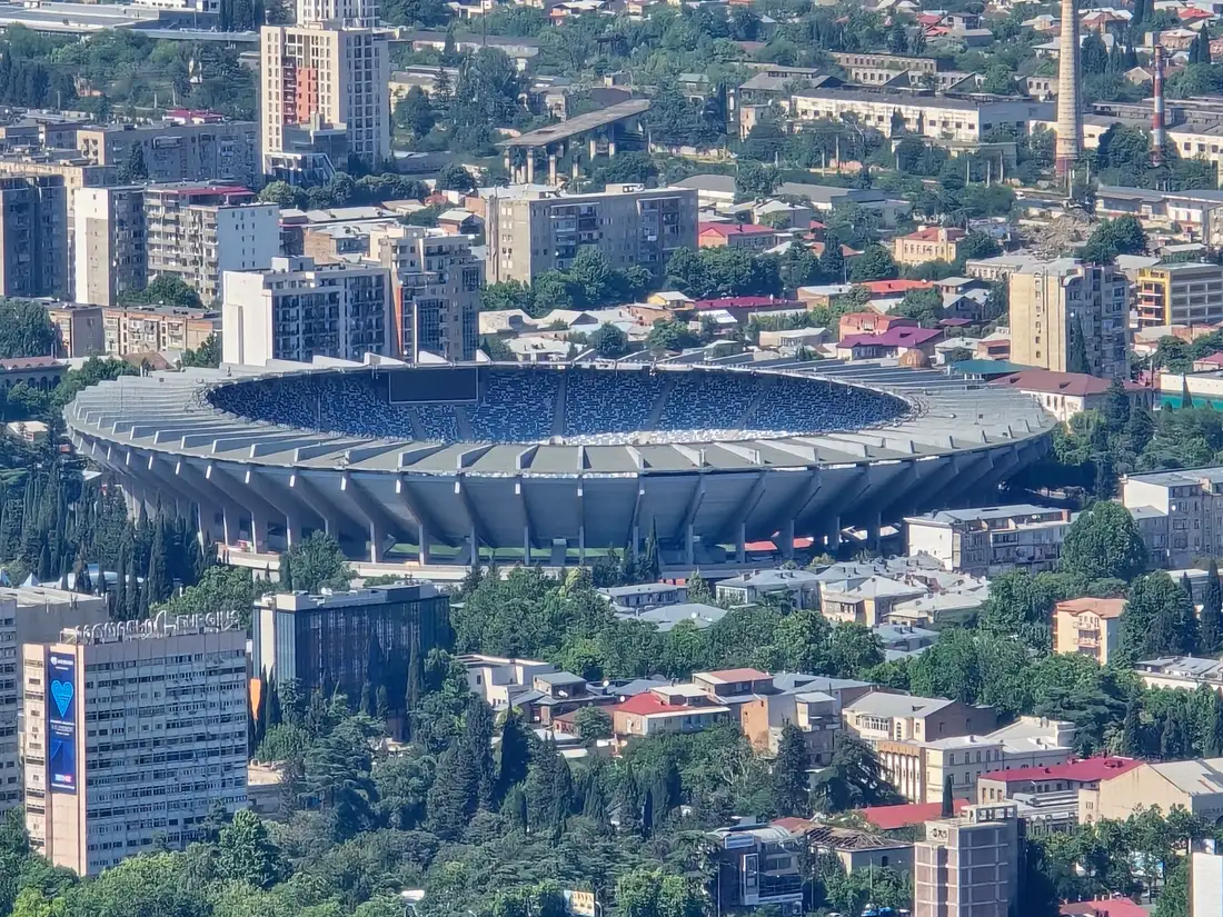 Aerial view of the oval Dinamo Arena stadium in Tbilisi surrounded by apartment blocks and trees