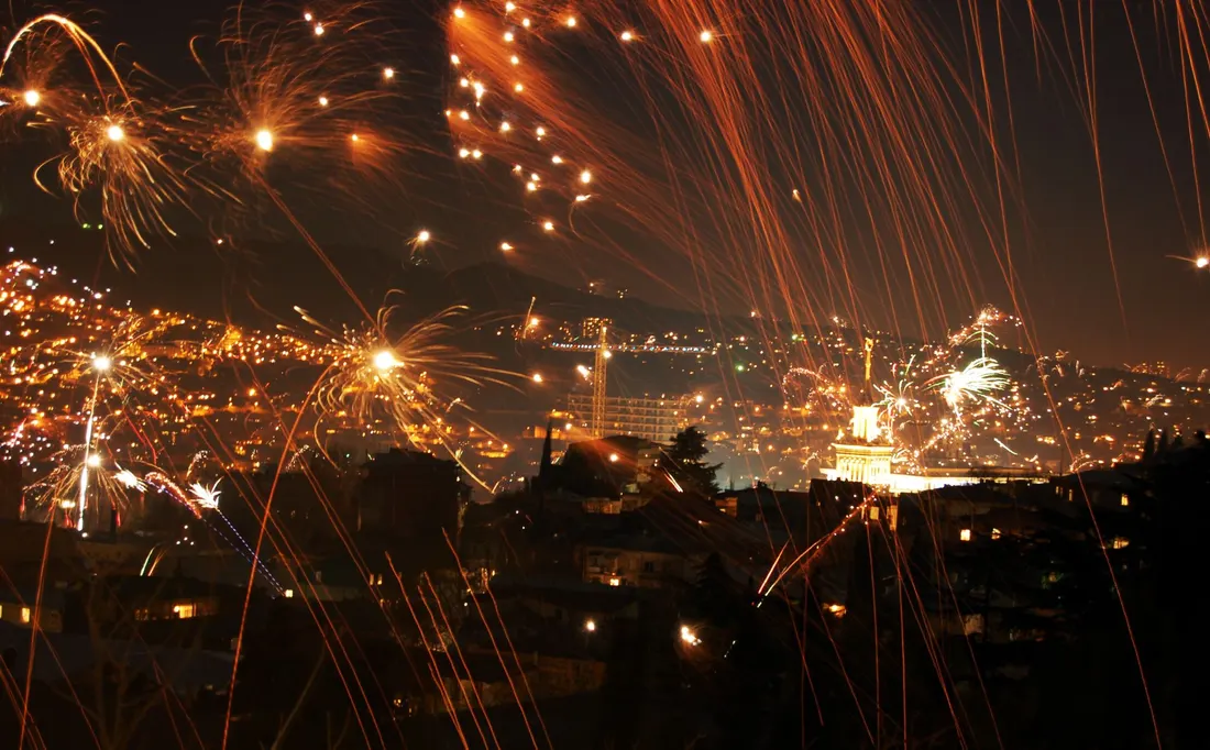 Streaks of fireworks over the lights of Tbilisi seen from a hillside just after midnight