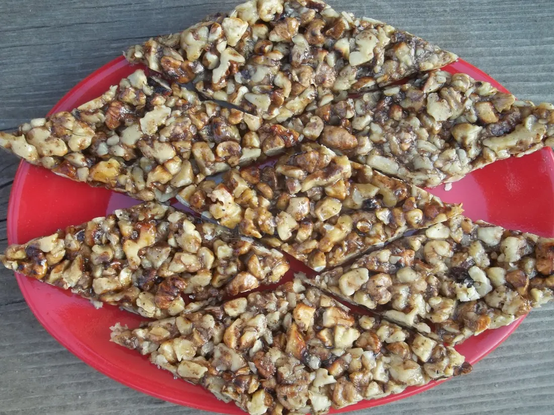 Diamond-shaped pieces of gozinaki, walnuts set in honey, on a red plate