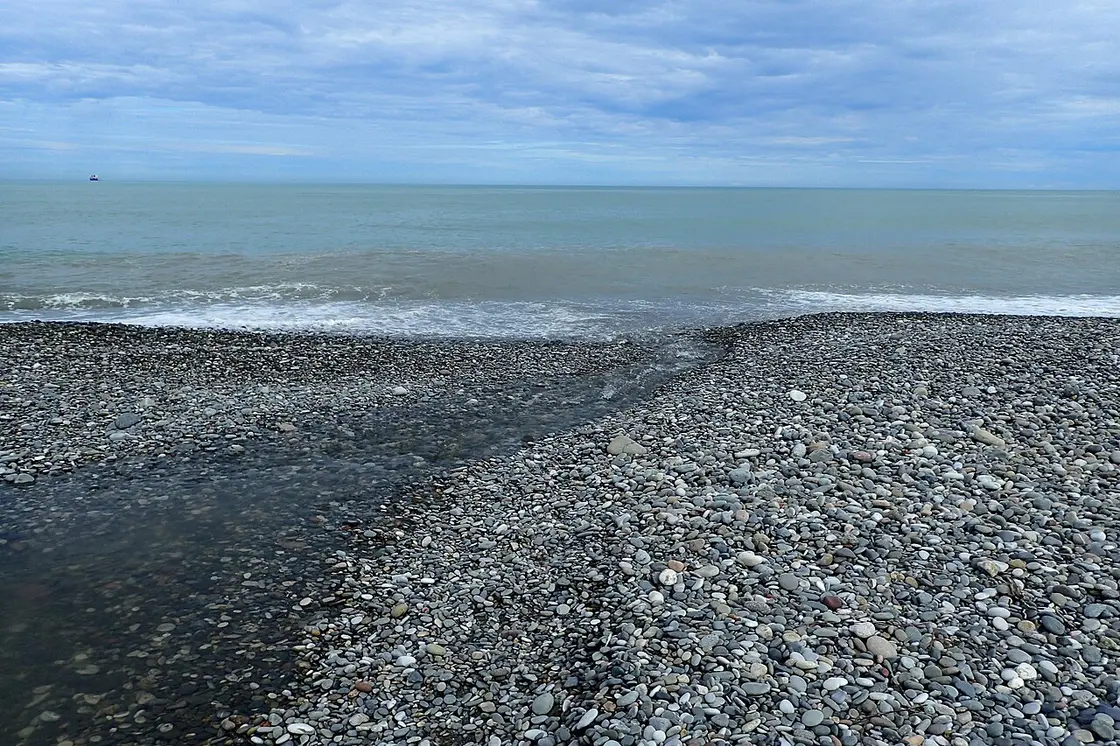Pebble beach at Mahinjauri with a stream flowing into the Black Sea