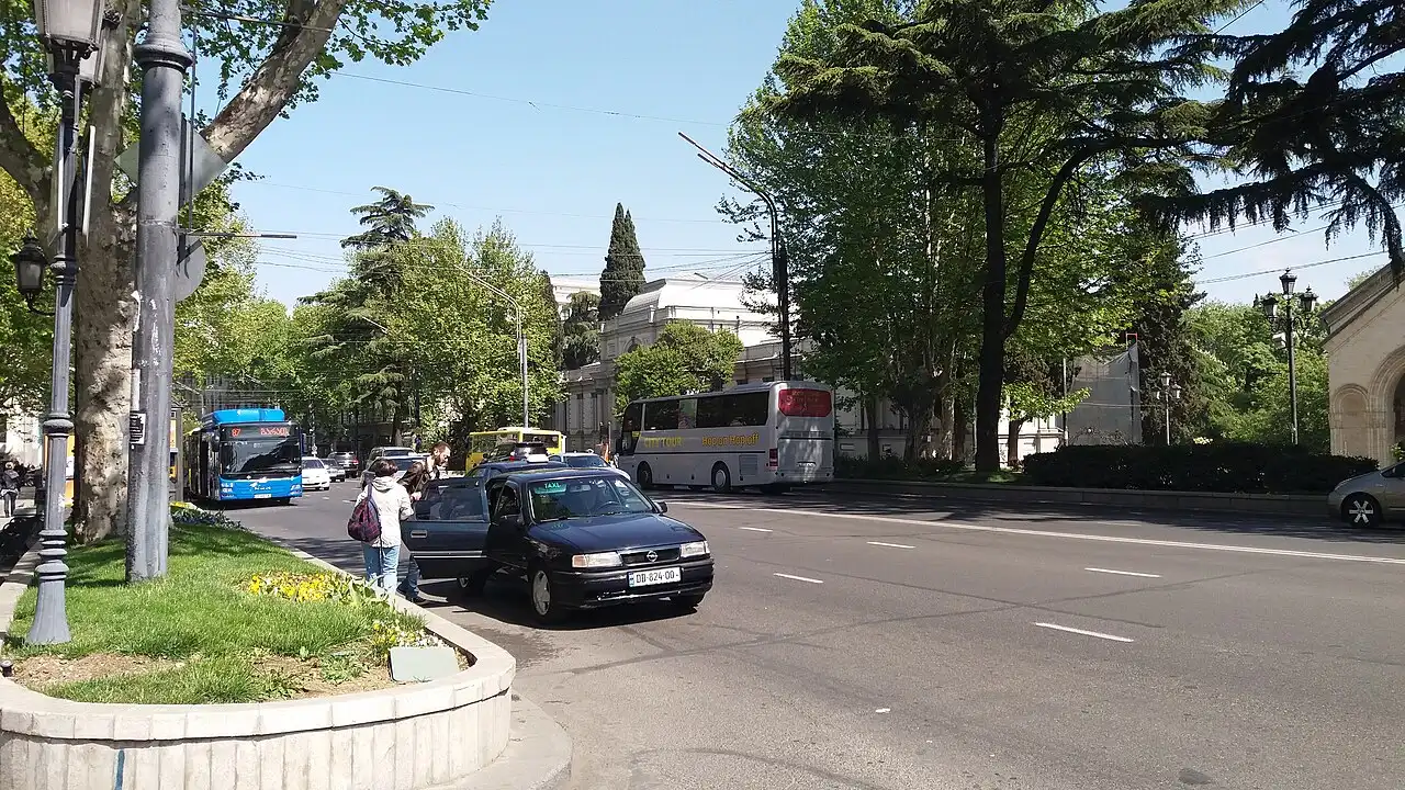A taxi at the kerb on Rustaveli Avenue in Tbilisi with a tour bus alongside