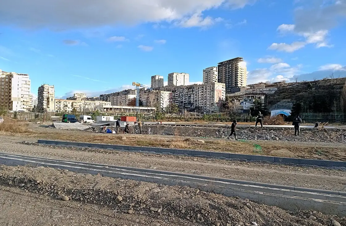 Workers on a construction site in Tbilisi with residential towers behind them