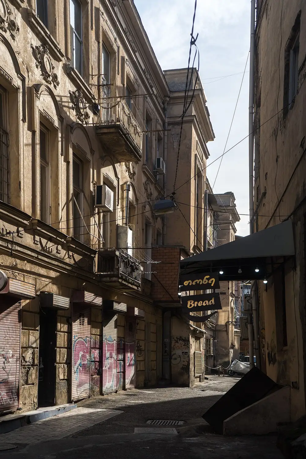 Narrow street in old Tbilisi with balconies and a bakery sign