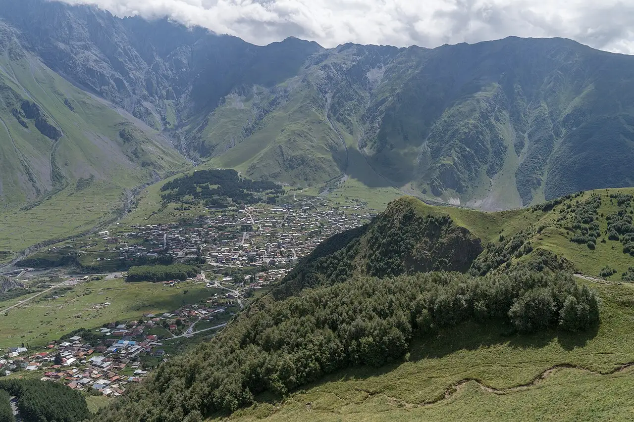 View of Stepantsminda village and the green Kazbegi mountains from the trail to Gergeti church