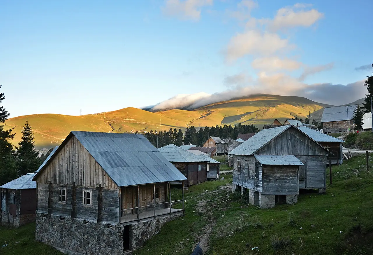 Timber houses on stone bases at Beshumi with the alpine meadows of Adjara behind