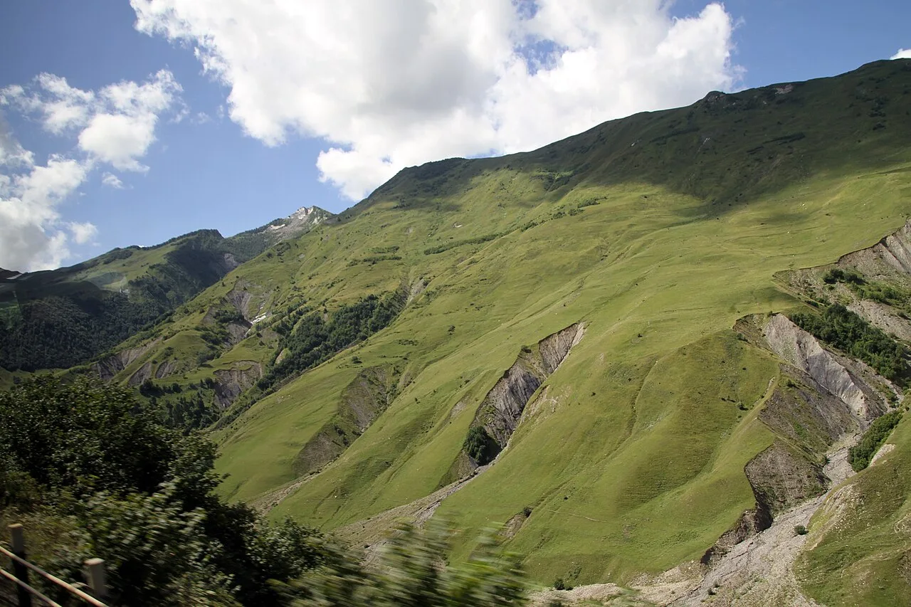 An eroded, rutted section of the Georgian Military Road cutting through mountain terrain