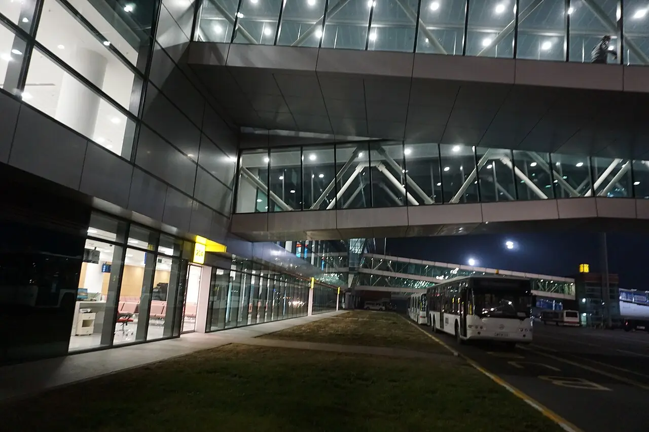Tbilisi airport's modern terminal at night with a city bus at the exit