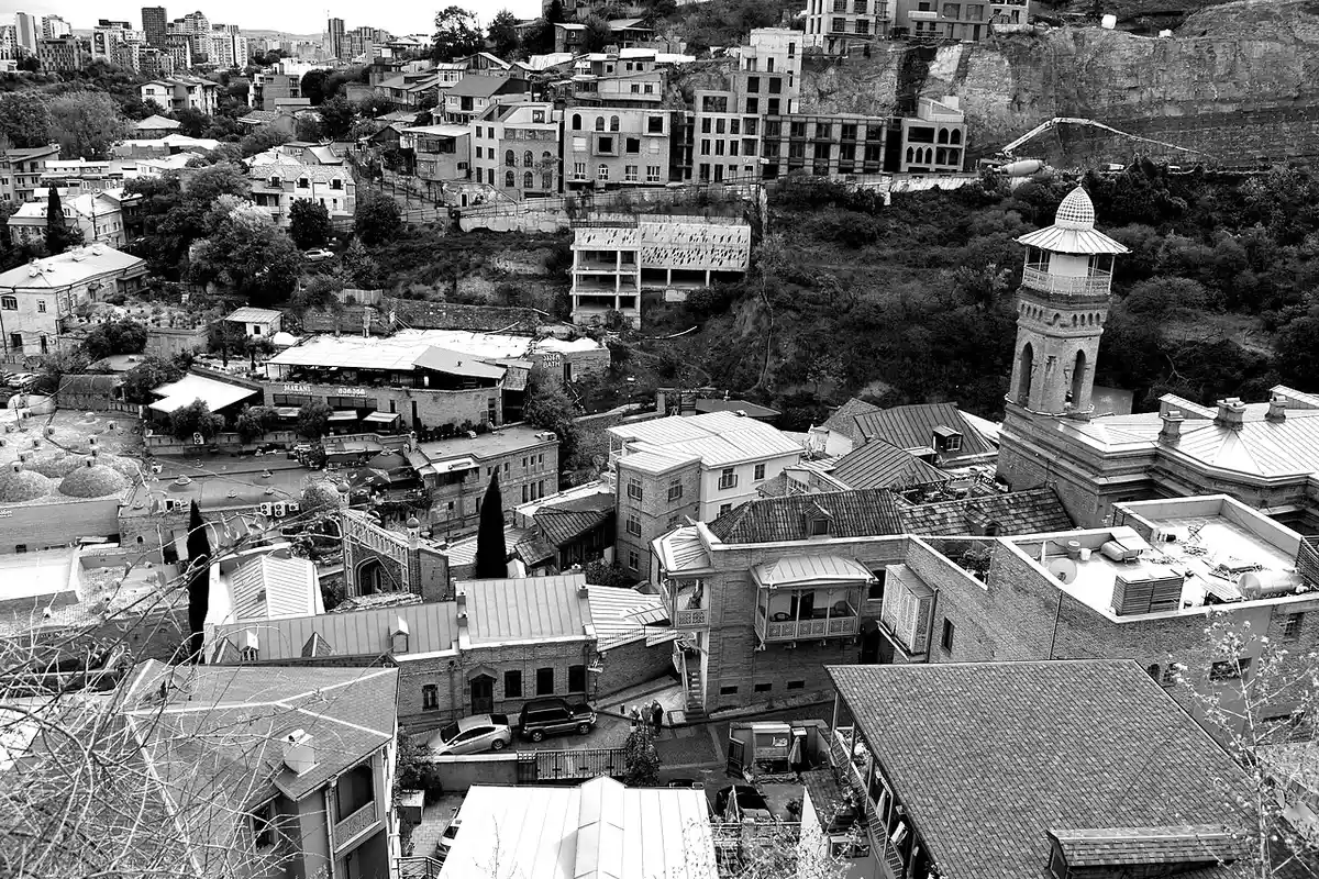 Black-and-white aerial view of Old Tbilisi rooftops, showing sulphur bath domes and a minaret