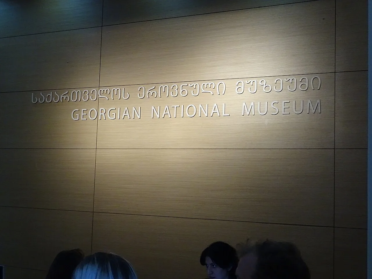 A Georgian National Museum sign at the entrance, with visitors standing below it