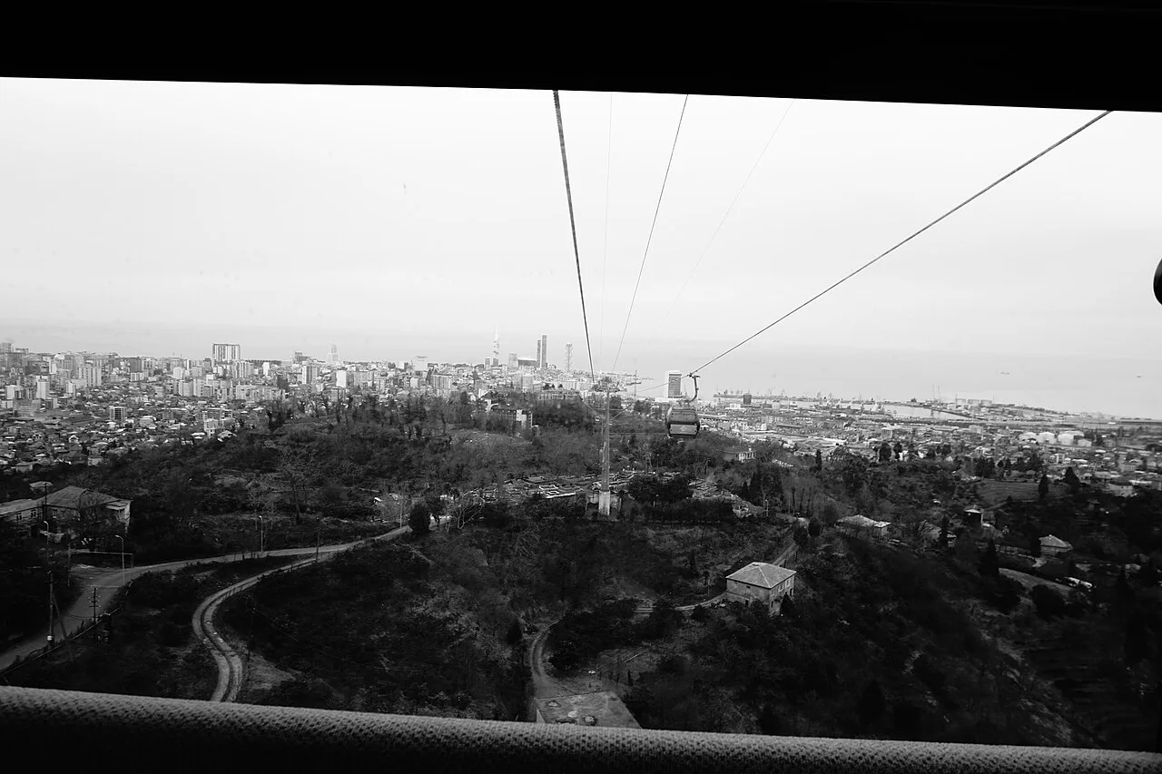 Black-and-white view from inside the Argo cable car cabin over the rooftops and port of Batumi