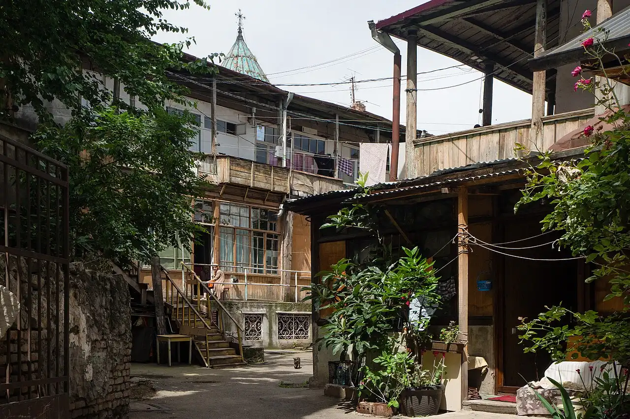 A courtyard in Old Tbilisi with wooden balconies, laundry hanging and a church dome in the background