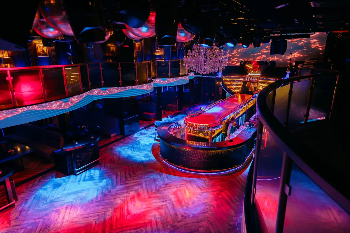 The multi-level hall of Teatro with red-and-blue lighting and a dance floor