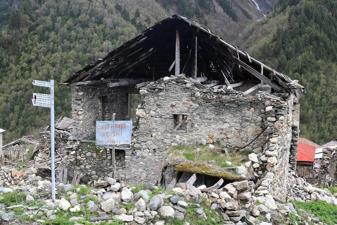 A stone guesthouse in Adishi with a trail signpost to Khalde and Iprari