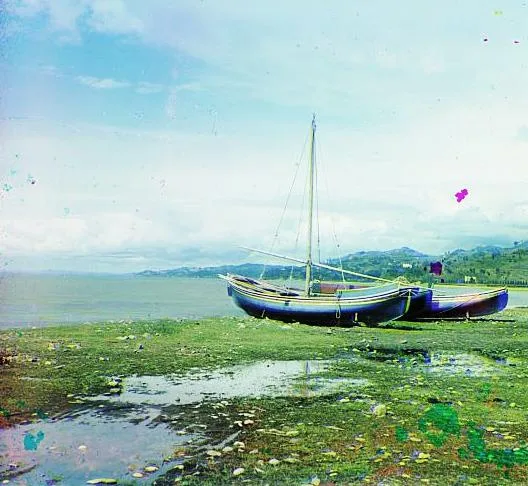 An early-20th-century colour photograph of fishing boats on the sea shore in Guria