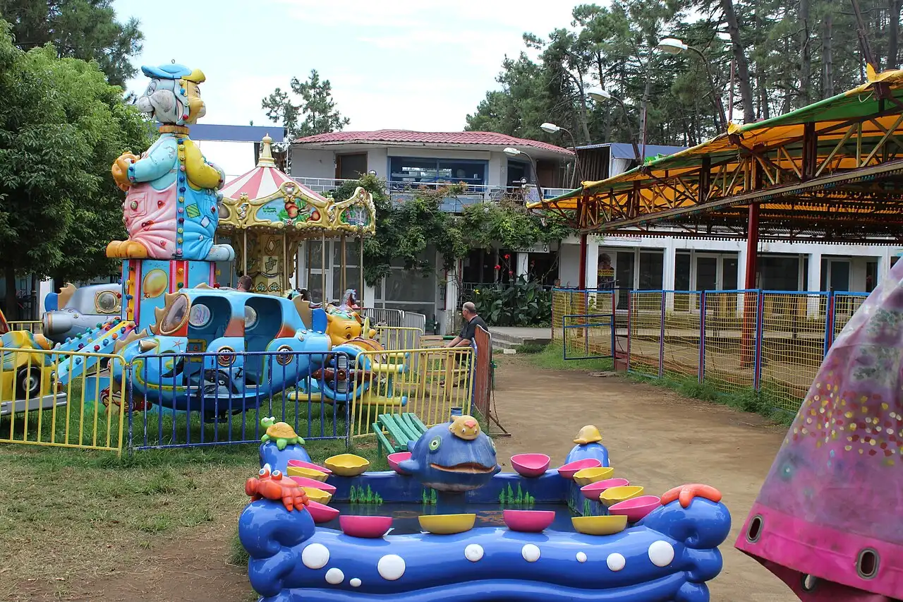 Children's rides in Ureki: a carousel and brightly coloured cars among the pines