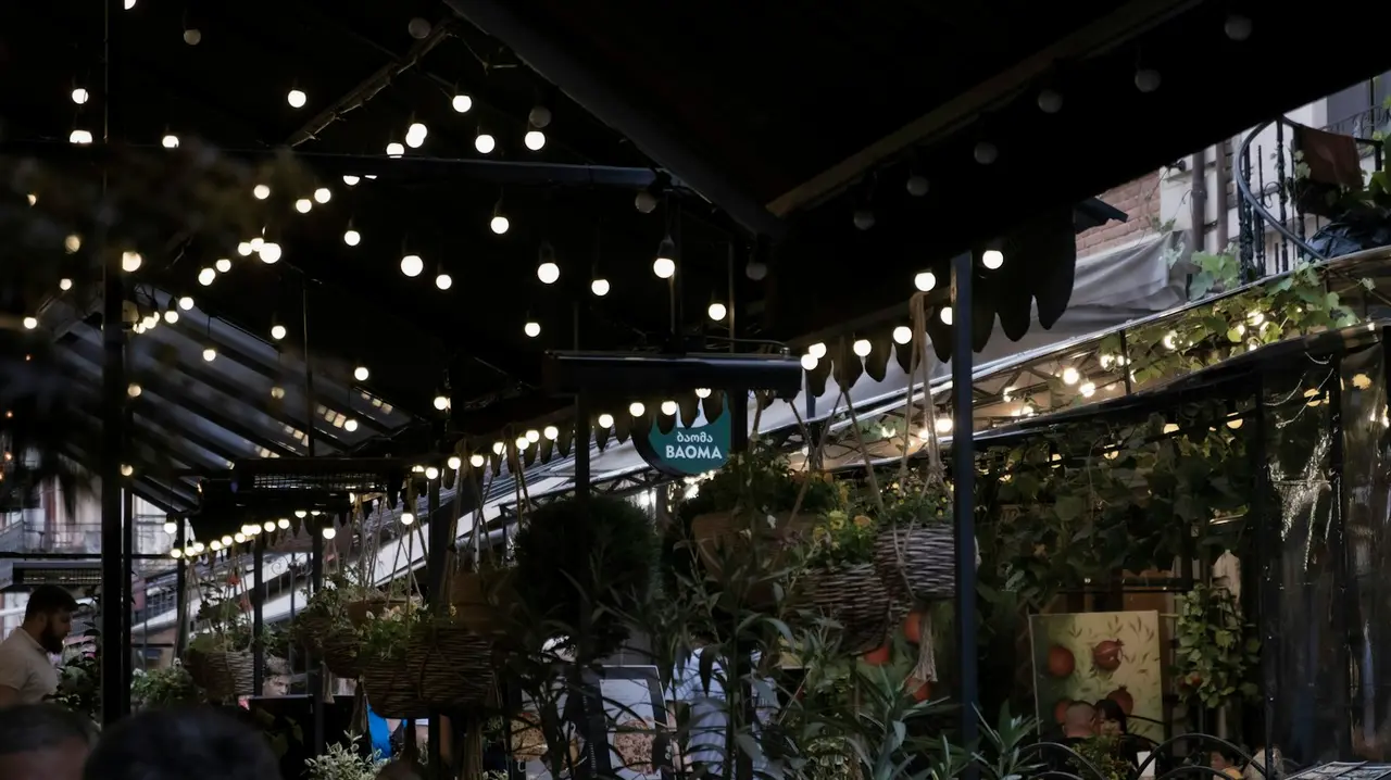 A cafe terrace in Tbilisi strung with lights, where cards are accepted