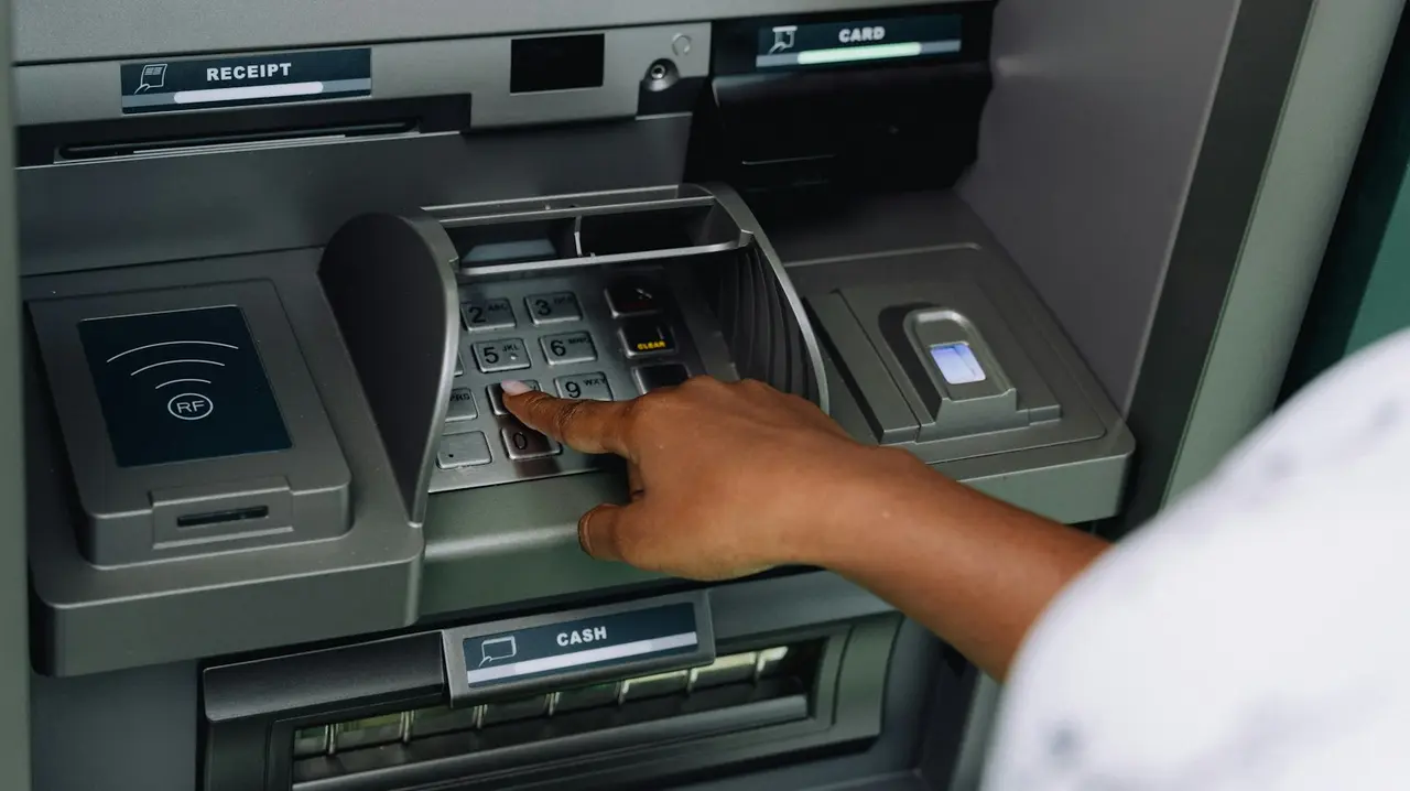 A hand entering a PIN on an ATM keypad