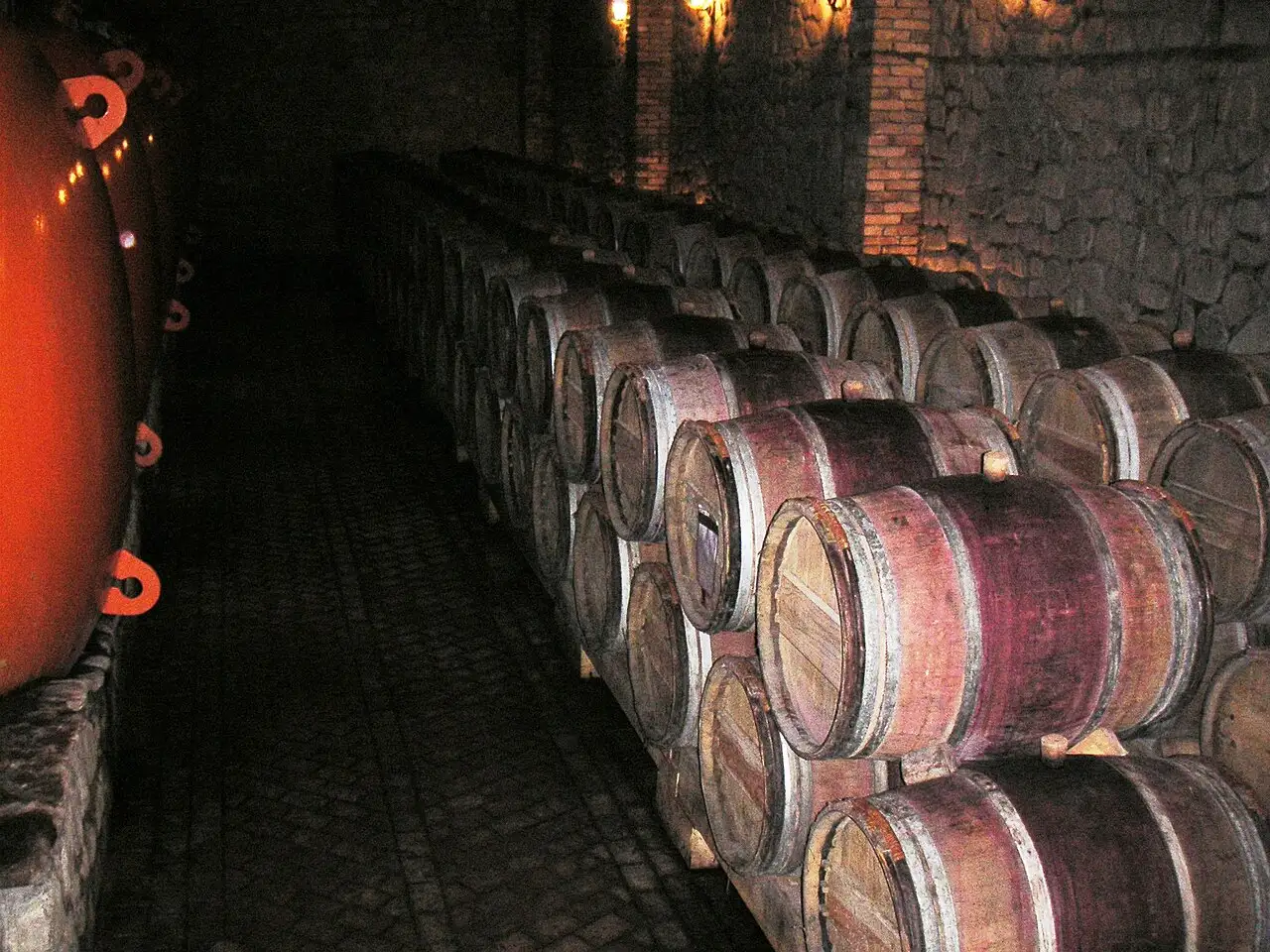 Rows of oak wine barrels in a stone cellar tunnel at Shumi Winery in Kakheti